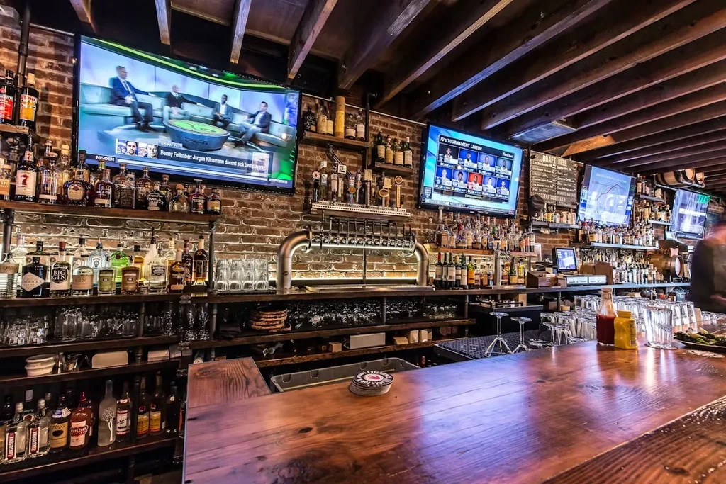 Well-stocked rustic bar with liquor bottles, beer taps, and sports TVs.