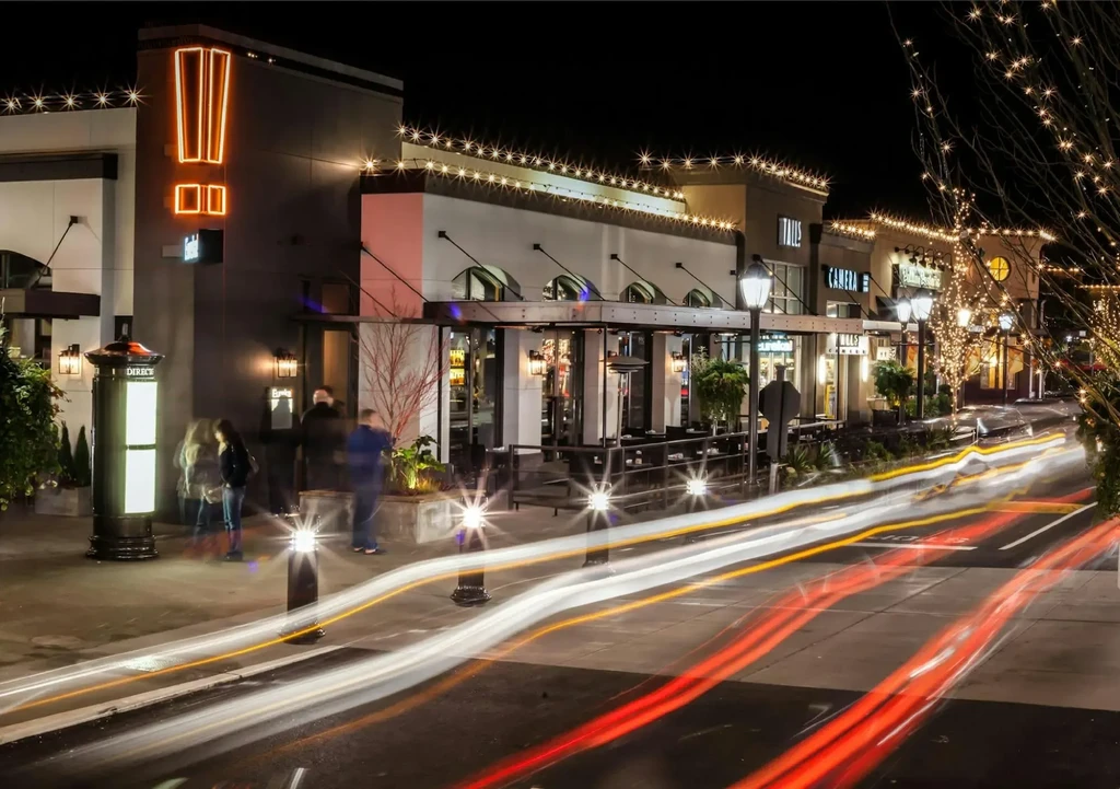 Night photo of a vibrant street with Eureka! restaurant and light trails.