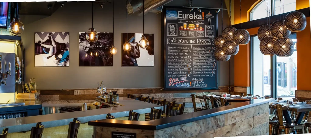 Industrial-chic restaurant interior featuring an L-shaped bar and chalkboard menu.