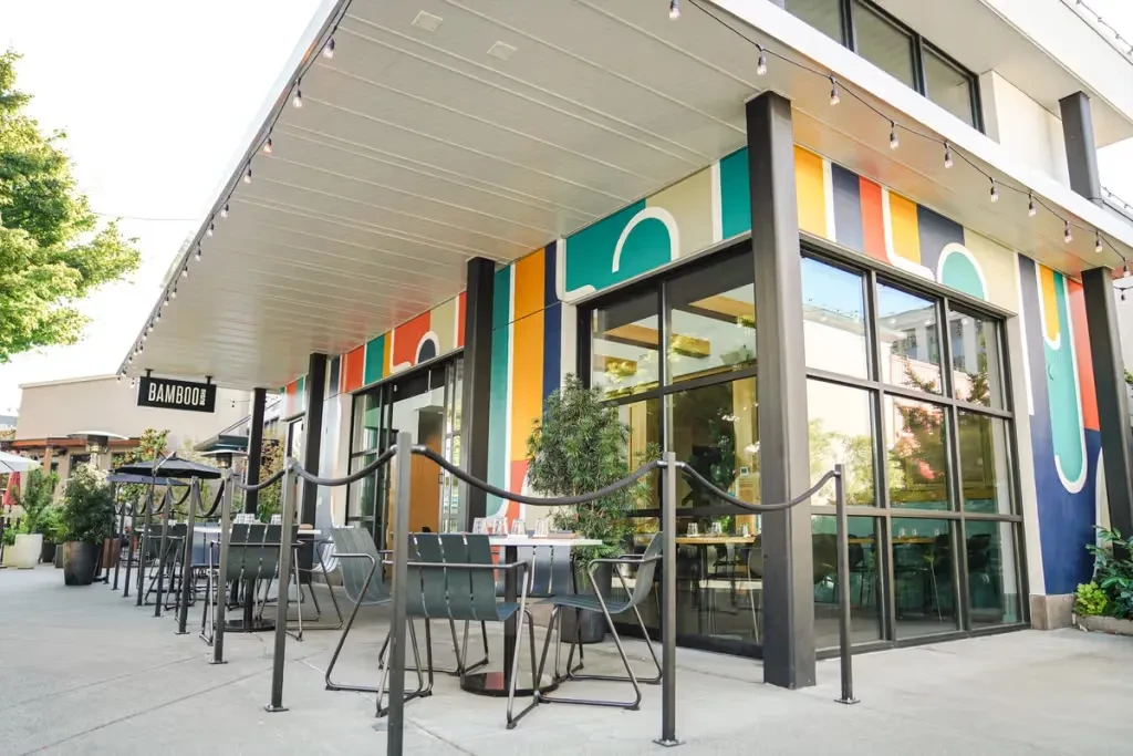 BAMBOO restaurant exterior with vibrant mural, patio seating, and string lights.