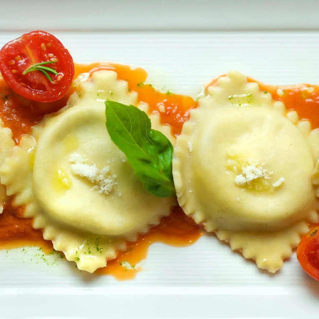 Ravioli with tomato sauce, parmesan, fresh basil, and cherry tomatoes.