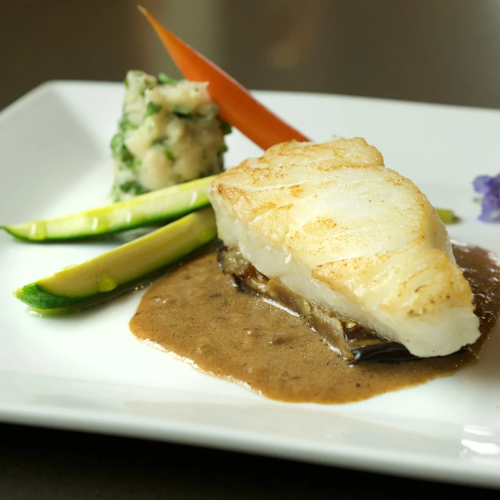 Pan-seared white fish with herbed mashed potatoes, zucchini, brown sauce.