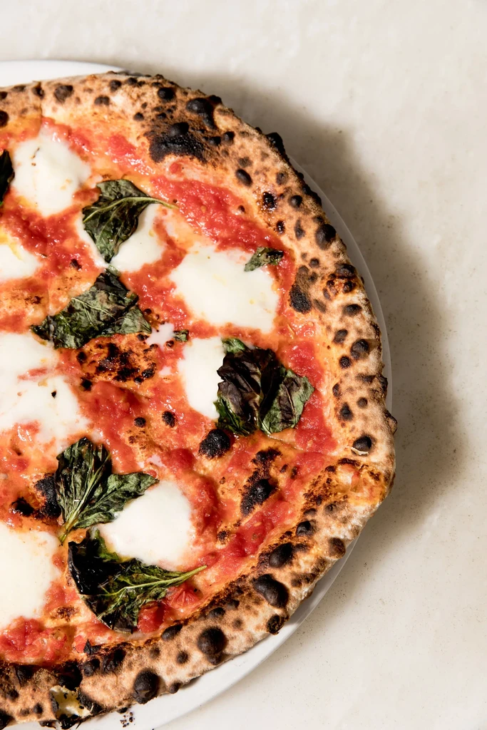 Overhead shot of freshly baked Neapolitan Margherita pizza with charred crust.