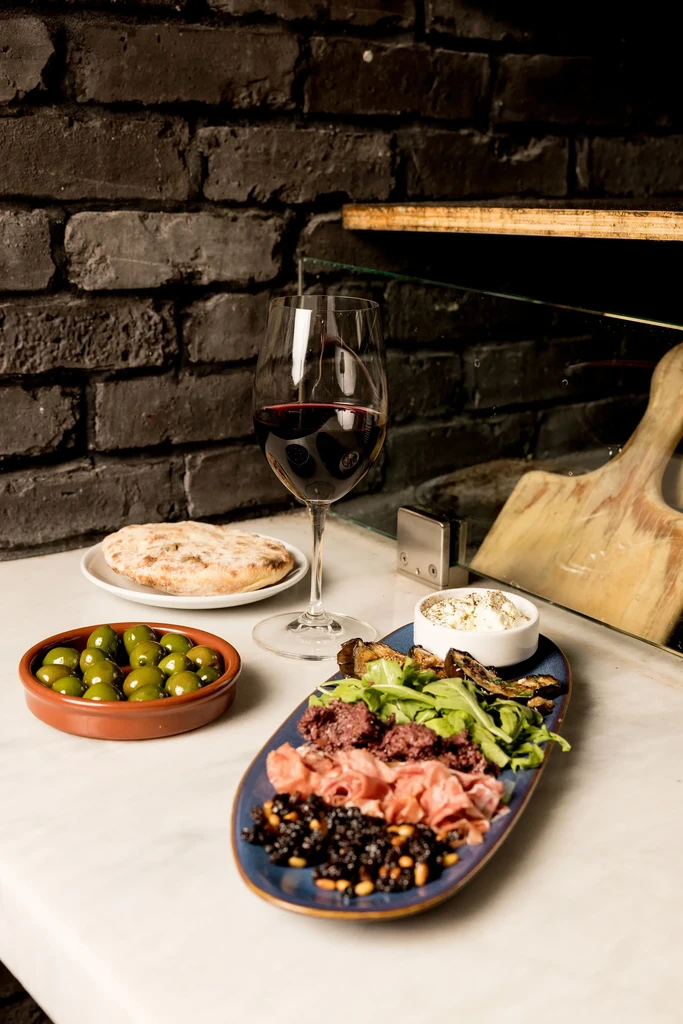 Appetizer platter, green olives, flatbread, and red wine.