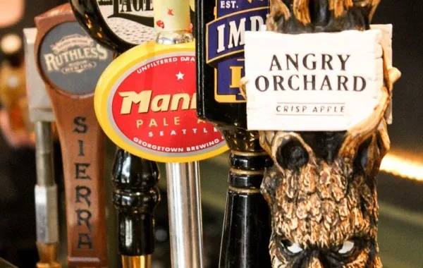 Branded beer and cider tap handles at a bar.