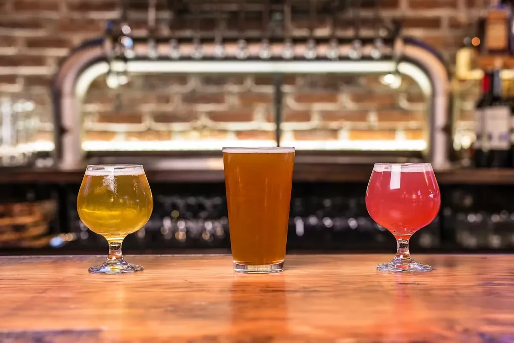 Three distinct colorful drinks on a bar with taps.