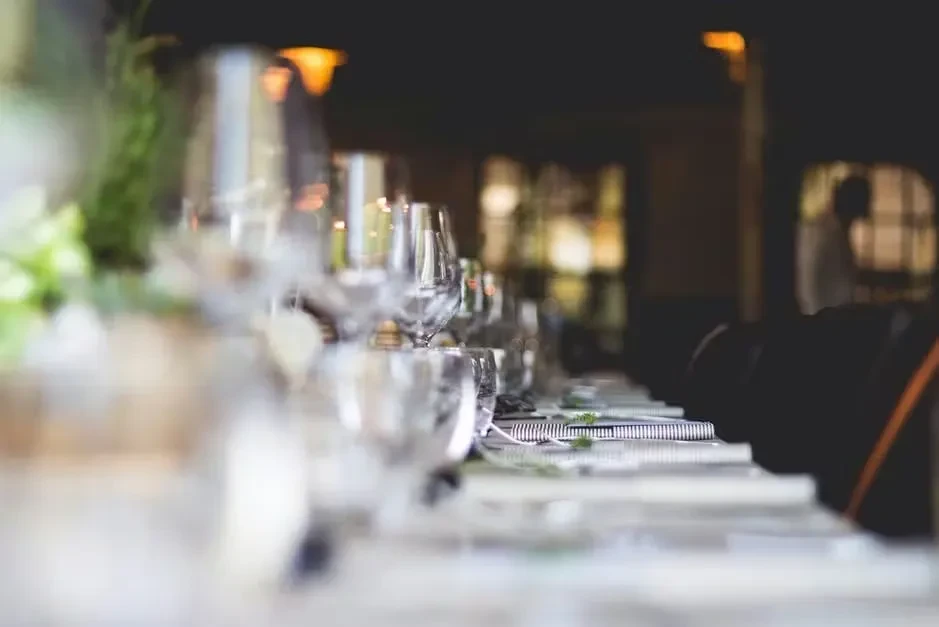 Elegant long dining table meticulously set with place settings in dim light.