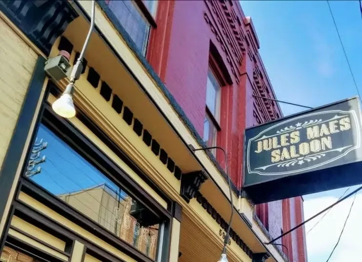 Ornate brick building with a "JULES MAES SALOON" sign.