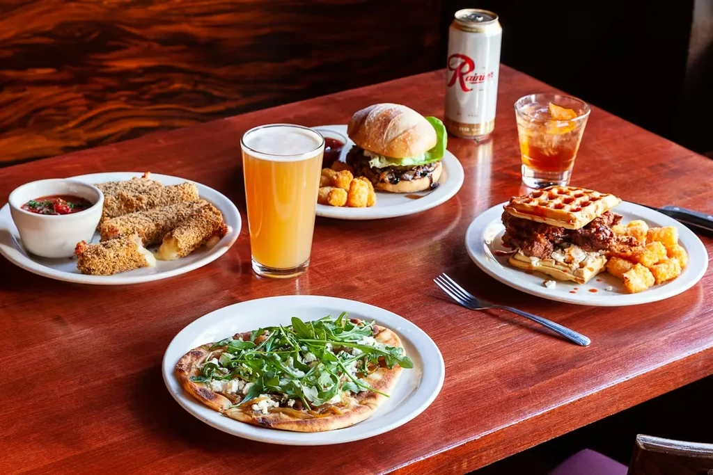 Overhead shot of assorted food dishes and beverages on a wooden table.