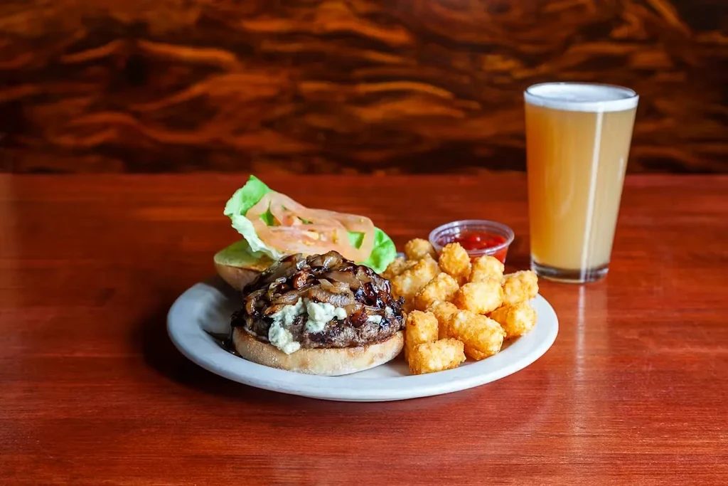 Burger with blue cheese, caramelized onions, tater tots, and a beer.