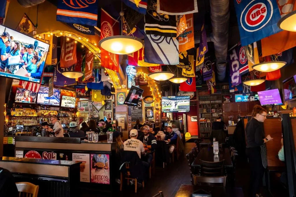 Vibrant sports bar interior with flags, TVs, bar, and patrons.