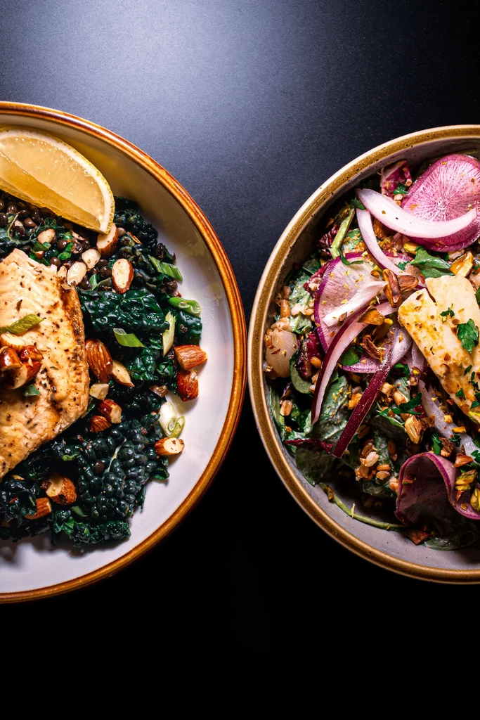 Two elegant bowls of healthy food: pan-seared fish and colorful salad.