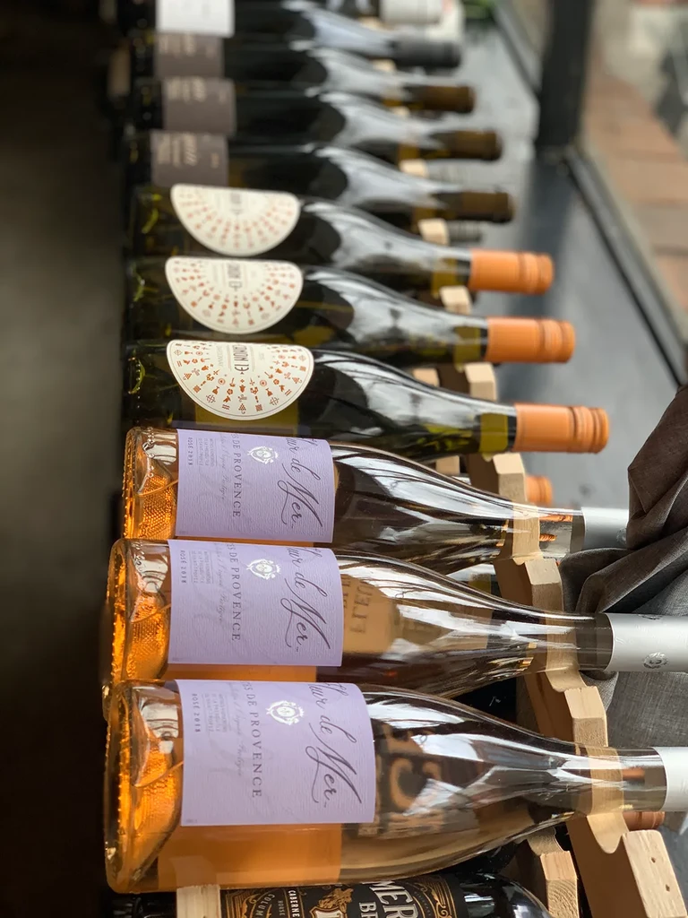 Rosé and white wine bottles neatly displayed in a wooden wine rack.