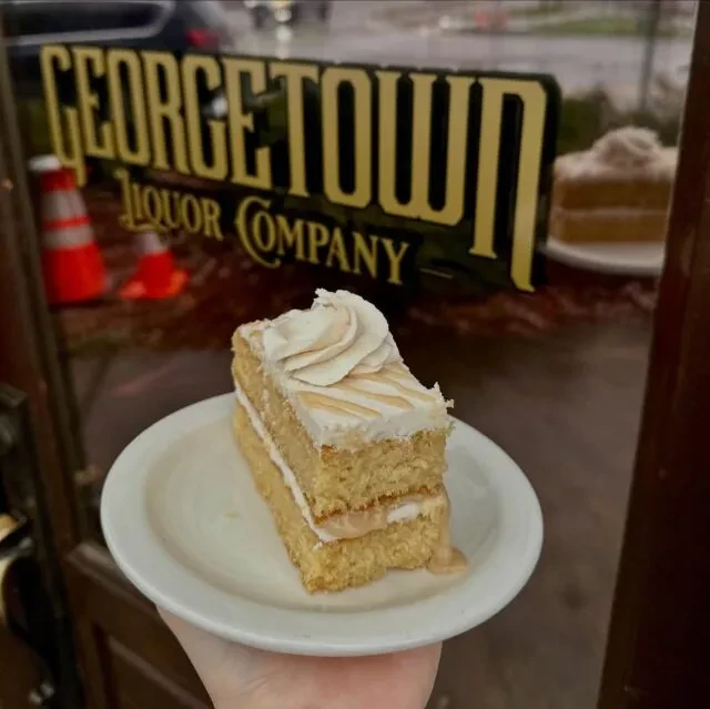 Close-up of cake slice with a bite, Georgetown Liquor Company sign in background.
