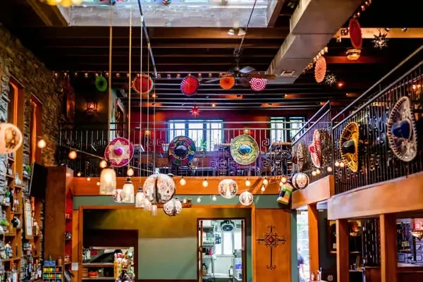 Multi-level Mexican restaurant interior with colorful sombreros, lights, and skulls.