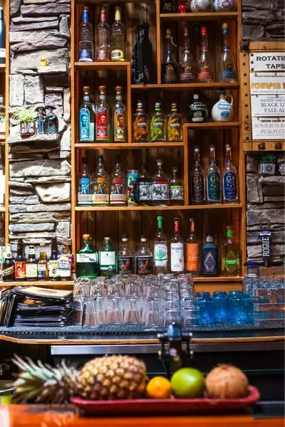 Rustic bar with shelves of tequila and mezcal, glasses, and fresh fruit.