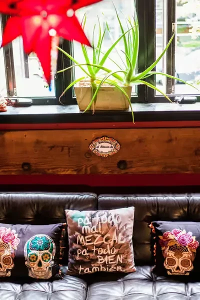 Mezcal-themed lounge with a leather couch, skull pillows, and mezcal quote.