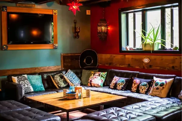 Cozy restaurant lounge with U-shaped sofa, colorful pillows, and eclectic decor.