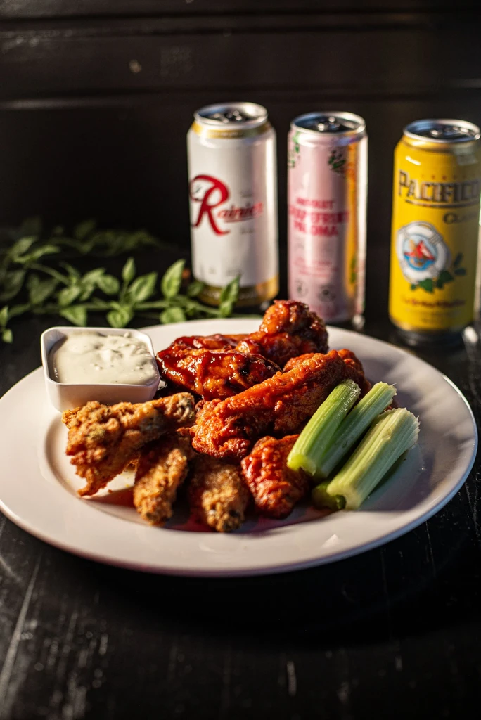 Crispy and sauced chicken wings, celery, dip, and three beverage cans.