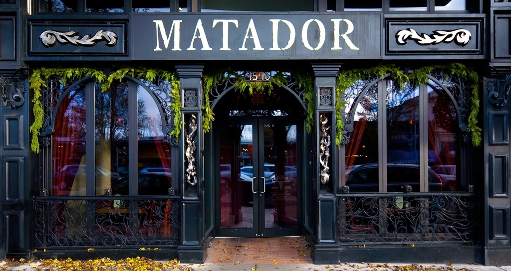 Autumn view of Matador restaurant's dark, ornate facade with green garlands.