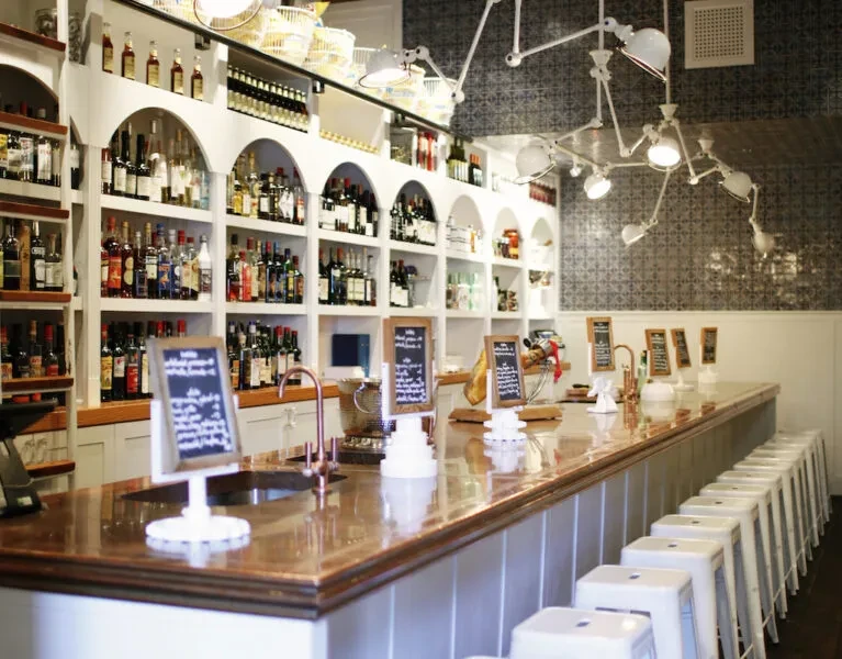 Empty bar with a polished copper counter and well-stocked shelves.