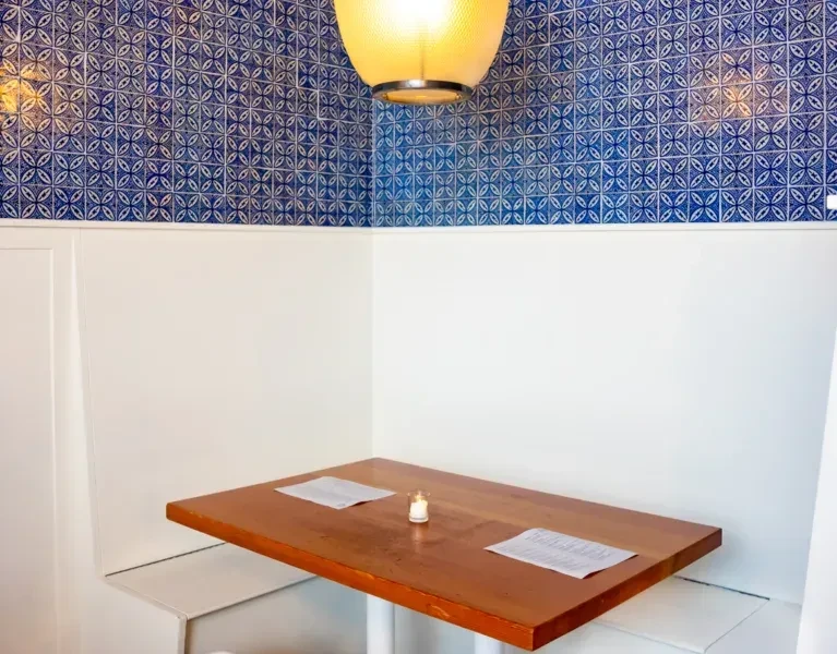 Restaurant corner booth with blue patterned tiles and a lit candle.
