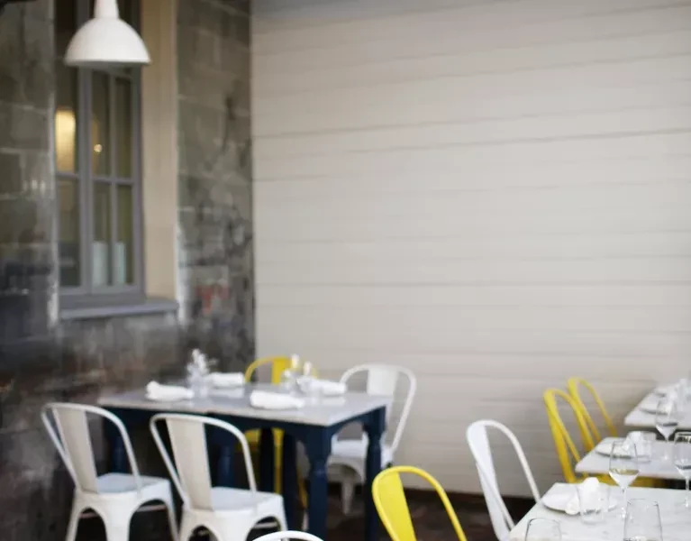 Modern cafe interior with empty dining tables, white and yellow chairs.