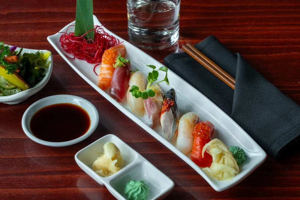 Colorful assorted nigiri sushi platter with ginger, wasabi, and soy.