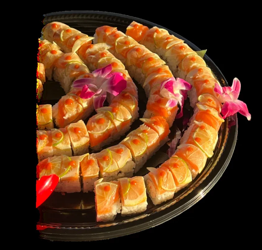 Serpentine sushi rolls on black tray, garnished with citrus, roe, orchids.