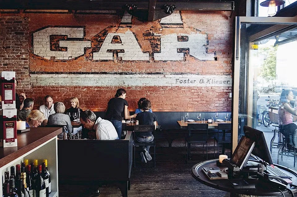 Restaurant interior with exposed brick wall painted "GAR Foster & Klieser."