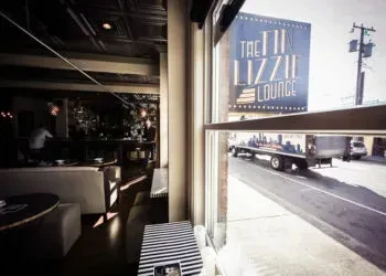 Inside dark lounge, looking out at 'The Lizzie Lounge' street sign.