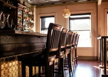 Four wooden bar stools at a dark wooden bar counter.