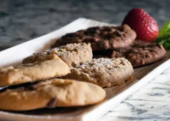 White plate filled with assorted cookies and a red strawberry.