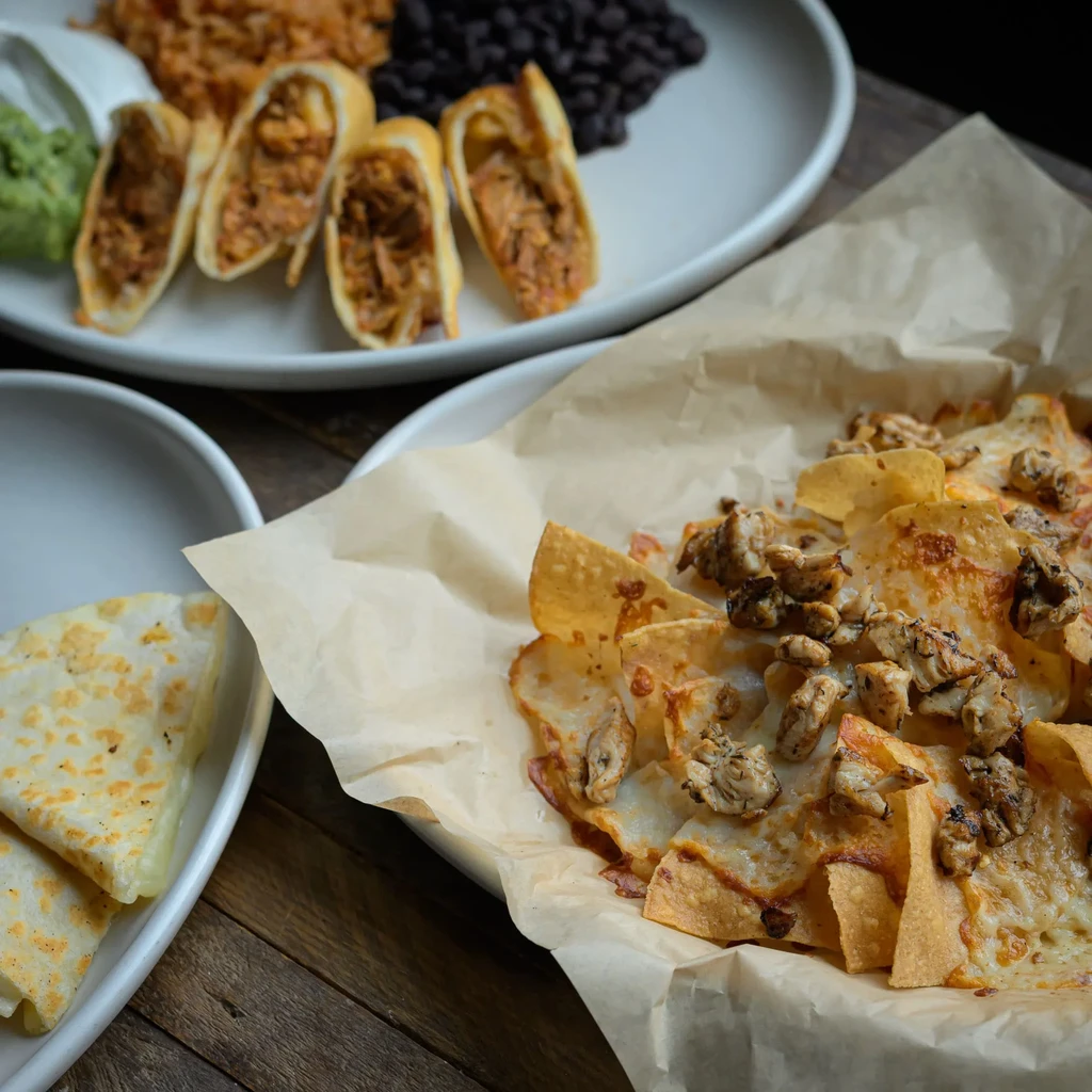 Mexican food spread: nachos, quesadilla, taquitos, rice, beans, guacamole.