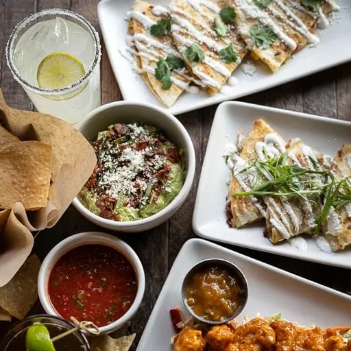 Overhead view of a diverse Mexican food spread on a wooden table.