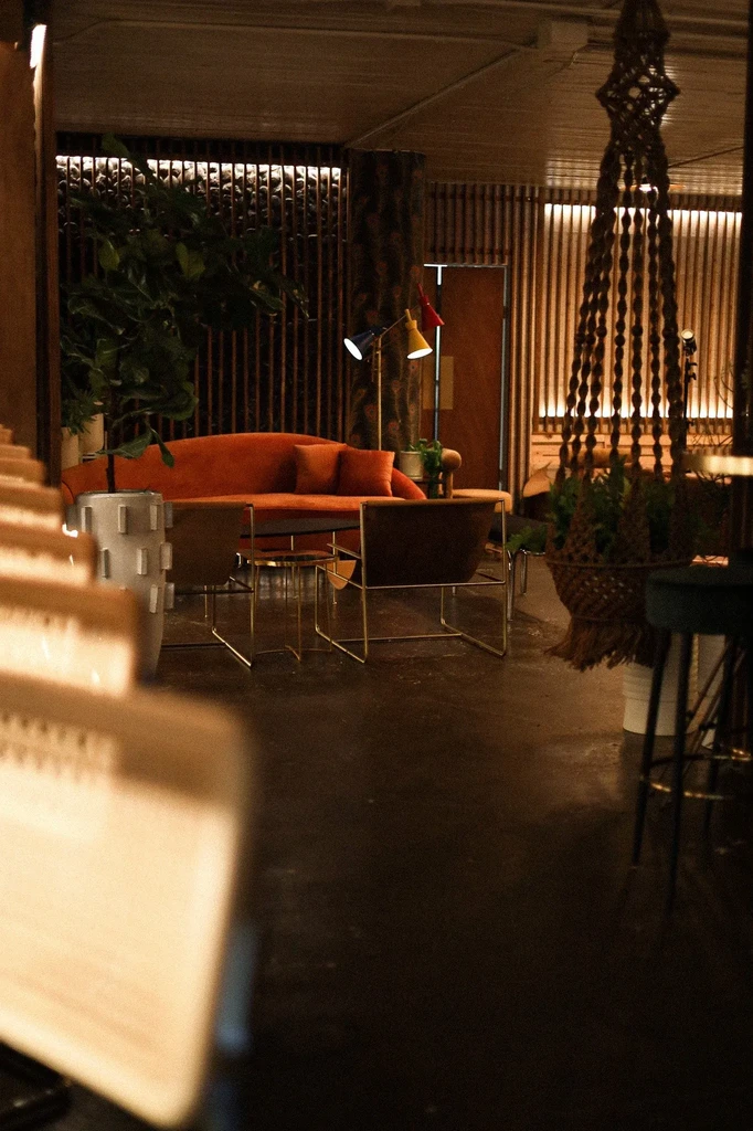 Modern-retro lounge interior with orange sofa, slatted wall, and vibrant lamp.