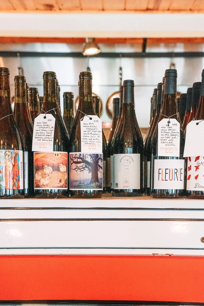 Labeled wine bottles with price tags on a display shelf in a restaurant.