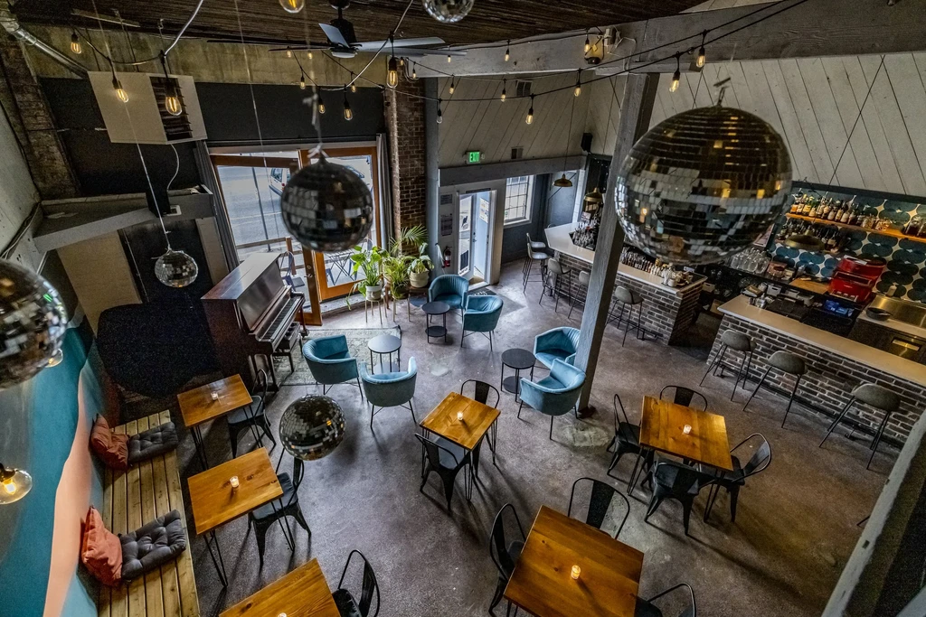 Empty industrial-chic restaurant interior showing bar, seating, and decor.