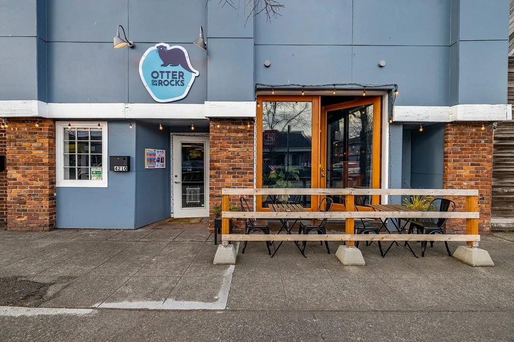 Modern blue-grey Otter on the Rocks restaurant exterior with patio.