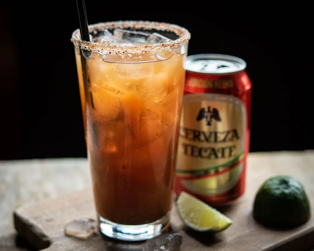 Spicy Michelada in salt-rimmed glass, with lime and Tecate beer.
