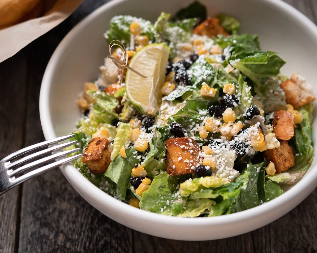Vibrant salad with lettuce, corn, black beans, cheese, and lime.