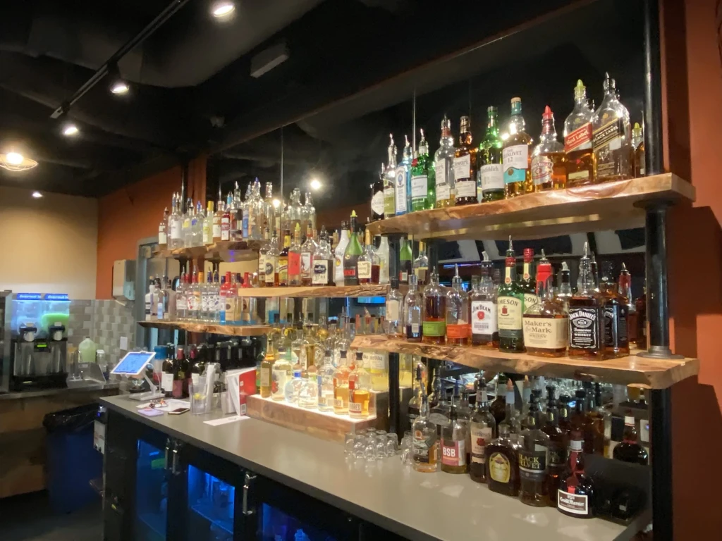 Multi-tiered liquor bottle display behind a dark bar counter.