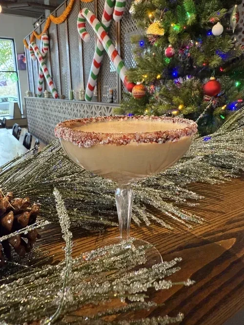 Creamy holiday cocktail in coupe glass, with sugared rim and Christmas decor.