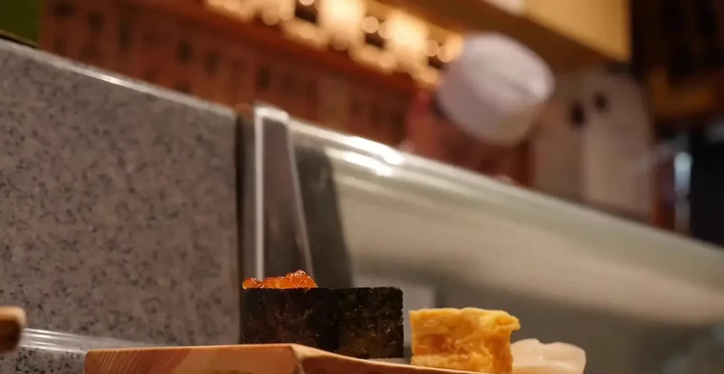 Sushi and tamago on a wooden board in a restaurant.