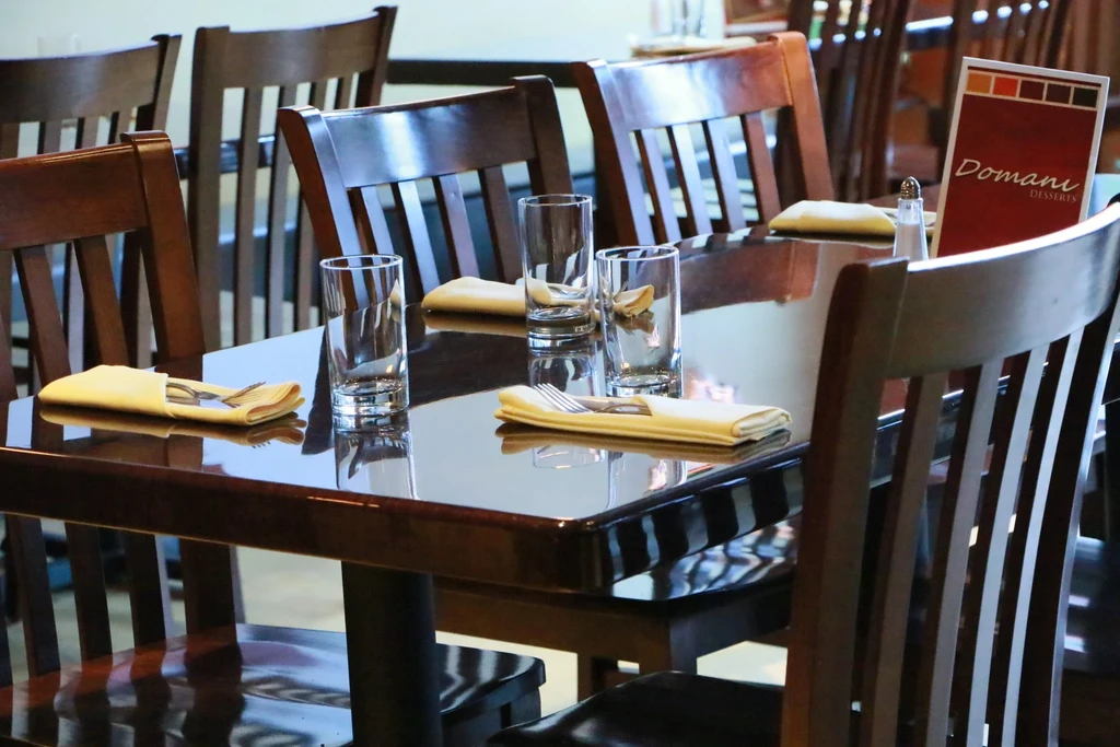 Reflective dark wooden table set for three with Domani Desserts menu.