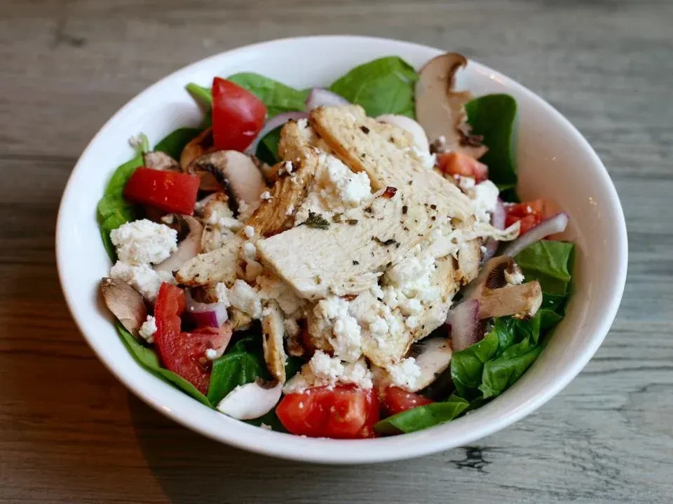 Fresh spinach salad with chicken, feta, tomatoes, mushrooms, and onion.