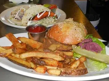 A burger with fries and tacos on a restaurant table.