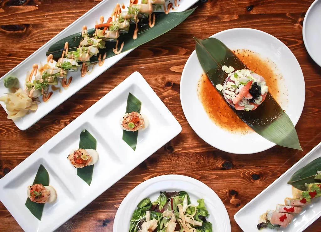 Variety of artfully plated Japanese dishes on a rustic wooden table.