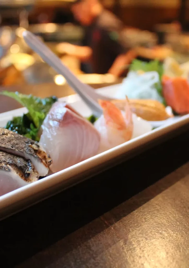 Arranged raw fish and seafood platter with garnishes on a white plate.