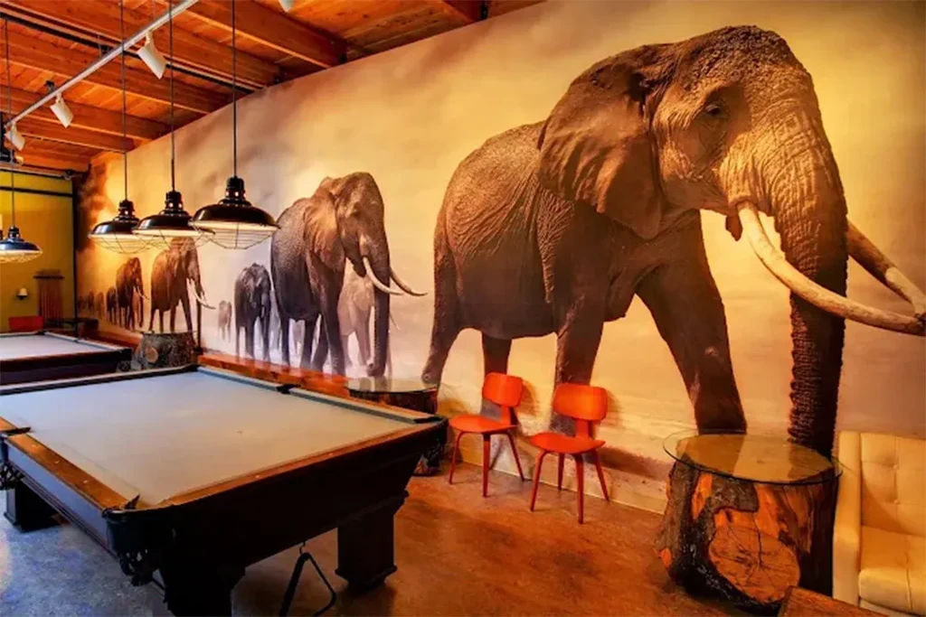 Industrial-rustic bar with pool tables and a striking elephant mural.